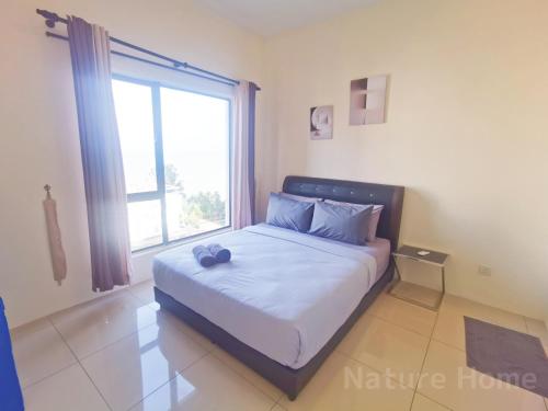 a bed in a room with a large window at Nature Home - Swiss Garden Resort Residences in Kuantan