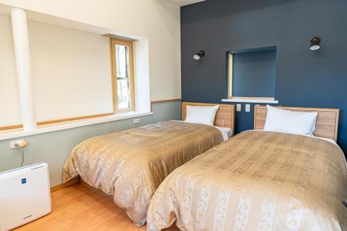 two beds sitting next to each other in a bedroom at Izumigo Yatsugatake Dog Paradise Cottage in Hokuto