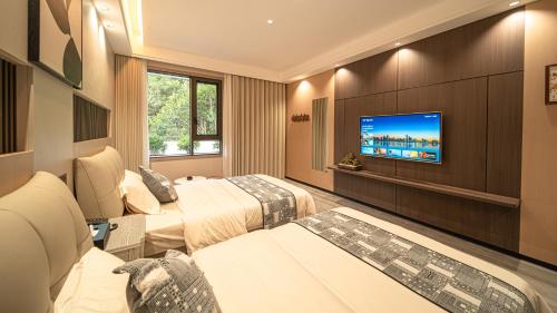 a hotel room with two beds and a flat screen tv at Xingfu Farm Resort in Zhangjiajie