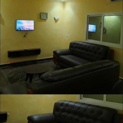a living room with a black couch and a tv at Résidence MK in Motsouémbé