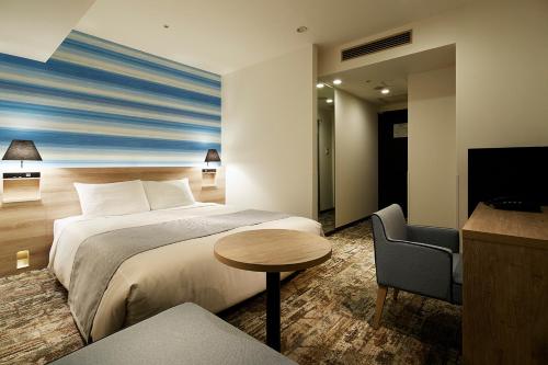 a hotel room with a bed and a table and a chair at Mitsui Garden Hotel Hiroshima in Hiroshima
