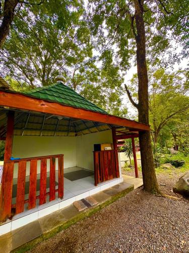 a small building with a green roof next to a tree at Puunee Wild River Villa's Borobudur in Borobudur