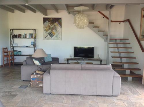 salon z kanapą, telewizorem i schodami w obiekcie La Villa Paille en Queue w mieście Saint-Gilles les Bains