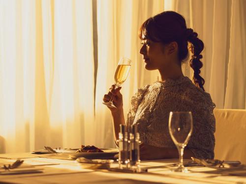 a woman sitting at a table with a glass of wine at Nagasaki International Hotel in Omura