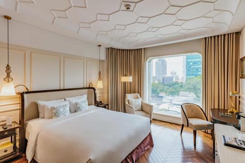 a hotel room with a bed and a large window at Hotel Des Arts Saigon Mgallery Collection in Ho Chi Minh City