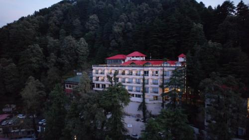 a large building with red roofs on a mountain at Regenta Place Dalhousie at Mall Road in Dalhousie