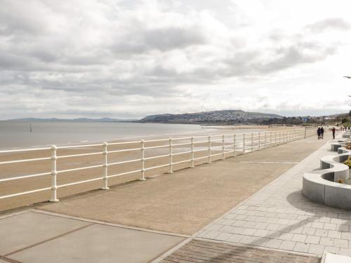 a white fence next to a beach with the ocean at Seawinds in Colwyn Bay