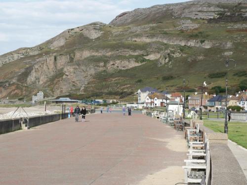 people walking on a boardwalk with a mountain in the background at Seawinds in Colwyn Bay