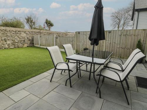 a patio with a table and chairs and an umbrella at 3 Parc Delfryn in Brynteg