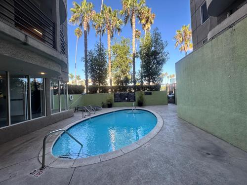 a swimming pool in the middle of a building with palm trees at Mid-City Charm 2BR Near LAs Hotspots! in Los Angeles