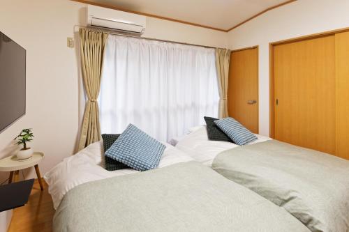 two beds in a room with a window at 10 minutes by train to Nagoya Station! Kominka guest house in Nagoya