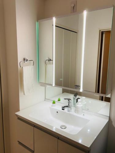 a bathroom with a white sink and a mirror at A newly built house a 4 minute walk from the station, Free parking & Let's enjoy the night view together! in Tokyo