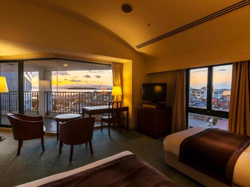 a hotel room with a bed and a dining area and a balcony at Nagasaki International Hotel in Omura