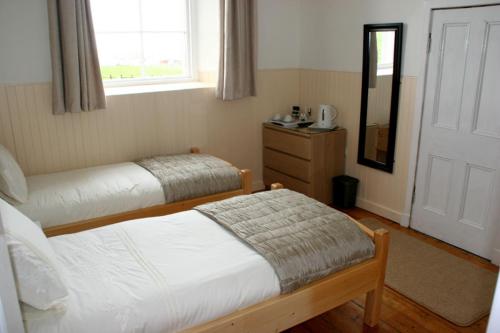 a bedroom with two beds and a dresser and a window at The Reid Hall in Pierowall