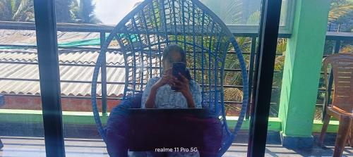 a person sitting in a hammock taking a picture in a mirror at Srujana Beach Homestay in Gokarn