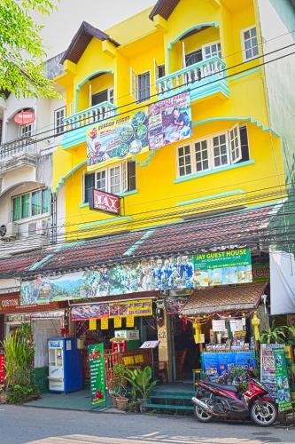 a yellow building with a motorcycle parked in front of a store at Jay Guesthouse and Restaurant (adult only) in Chiang Mai