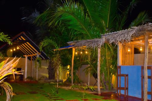 a house with a palm tree in the night at Jungle View Inn in Trincomalee
