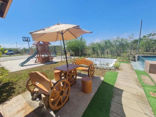 a table and chairs under an umbrella next to a pool at Balai Elmienna - solar powered farm house with pool in San Juan