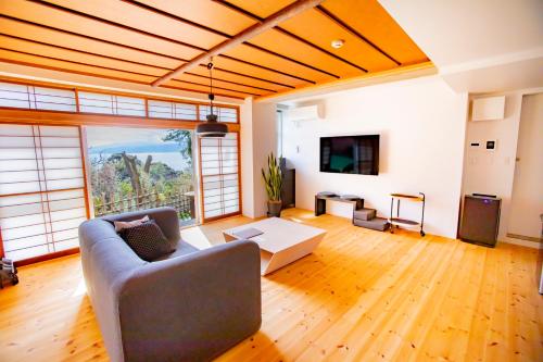 a living room with a couch and a tv at 真鶴町ペットと泊まれてBBQも可能落ち着く和モダンルームapartment Hotel途乃中 in Manazuru