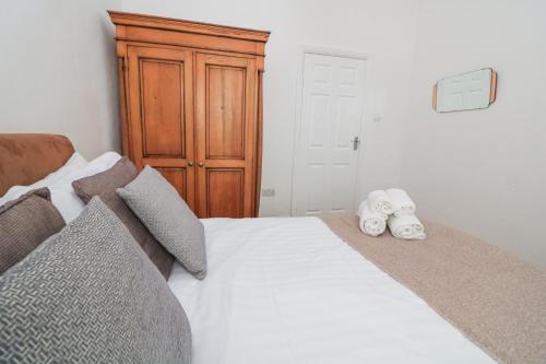 a bedroom with a white bed with a wooden cabinet at Delmonte Lodge in Torquay