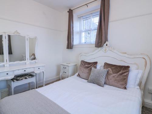 a bedroom with a white bed and a desk and mirror at Delmonte Lodge in Torquay