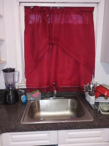 a kitchen sink in front of a red curtain at Country space in Rosedale