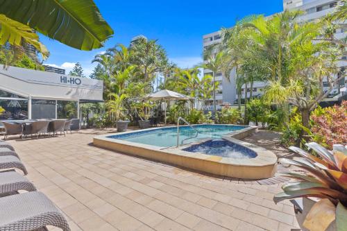 ゴールドコーストにあるHi Ho Beach Apartments on Broadbeachの椅子と木のあるリゾートのプール