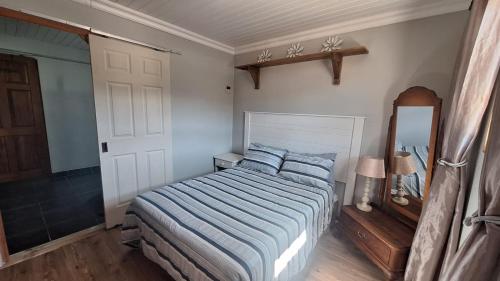 a bedroom with a bed with a blue striped comforter and a mirror at Nature's View - Dana Bay in Mossel Bay