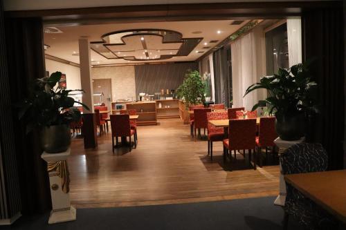 a dining room with tables and chairs and plants at Hotel Haarener Hof in Bad Wünnenberg