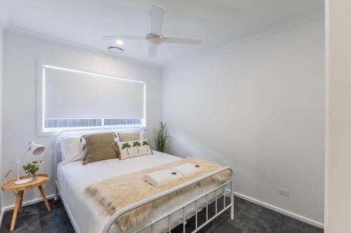 a white bedroom with a bed and a window at Lavender & Olive in Myrtleford
