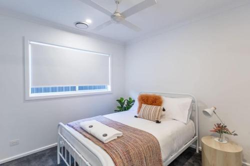 a white bedroom with a bed and a window at Lavender & Olive in Myrtleford