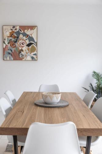 a dining room table with white chairs and a bowl on it at Lavender & Olive in Myrtleford