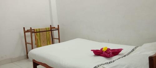 a white bed with a red flower on it at Akshaya Rest Maskeliya in Nikawatawana