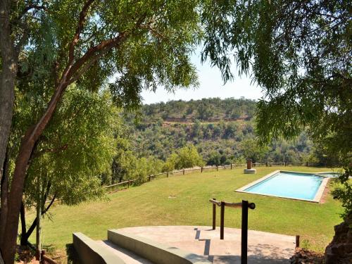 a swimming pool in a field with a tree at Elements Private Golf Reserve in Bela-Bela