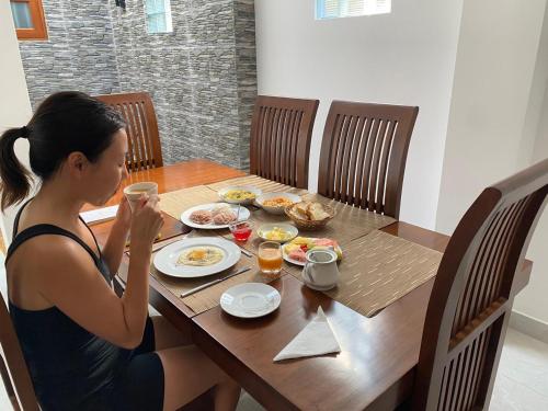 een vrouw die aan een tafel zit met een bord eten bij Sithuka Villa Bentota in Bentota