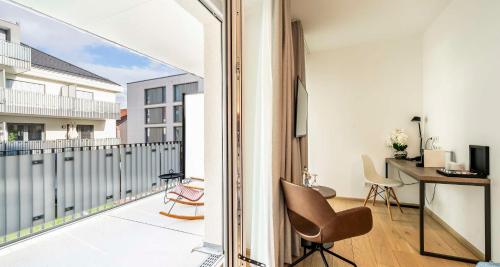 an apartment with a balcony with a desk and chair at Aiden by Best Western Biberach in Biberach an der Riß