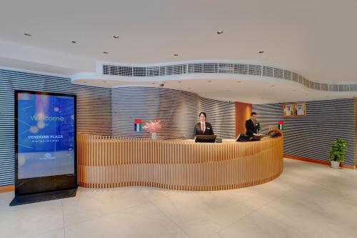 a lobby with two people sitting at a reception desk at Vendome Plaza Hotel in Dubai