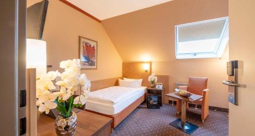 a hotel room with a bed and a vase of flowers at Sure Hotel by Best Western Hilden-Düsseldorf in Hilden