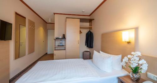 a bedroom with a white bed with a vase of flowers at Sure Hotel by Best Western Hilden-Düsseldorf in Hilden