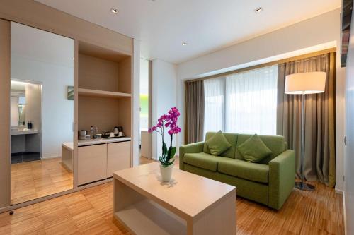 a living room with a green couch and a table at Hilton Garden Inn Venice Mestre in Mestre