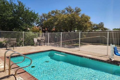 a small swimming pool with a fence and chairs at Baymont by Wyndham San Antonio Airport in San Antonio