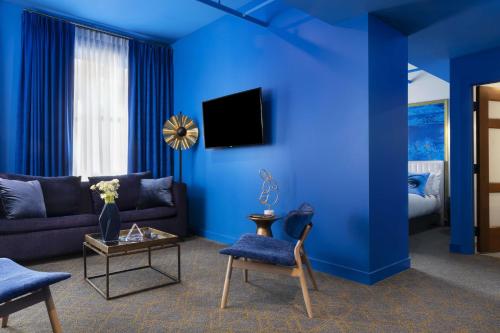 a blue living room with a couch and a table at Angad Arts Hotel St Louis, Tapestry Collection by Hilton in Saint Louis