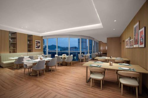 a restaurant with tables and chairs and a large window at Wyndham Hotel Guangzhou Huangbian Metro Branch - Free shuttle bus to Canton Fair in Guangzhou