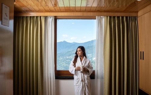 a woman in a robe standing in front of a window at Summit Grand Resort & Spa in Gangtok