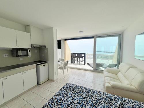 Il comprend un salon avec un canapé et une cuisine avec vue. dans l'établissement Studio 26C, Bat C Héliopolis Village Naturiste, au Cap d'Agde