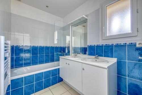 baño azul y blanco con lavabo y bañera en 3 pièces - Piscine - Proche plage, en Soulac-sur-Mer