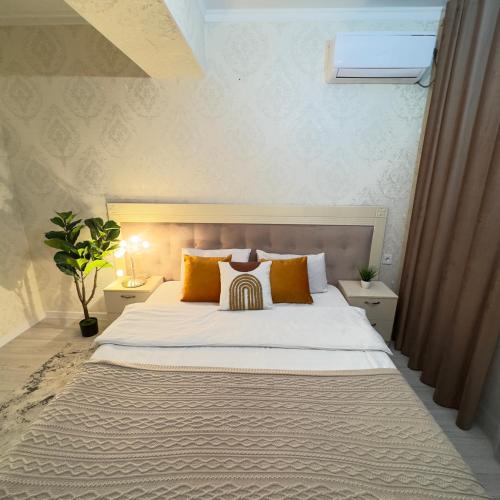 a bedroom with a large white bed with orange pillows at Urban Oasis 216 in Almaty