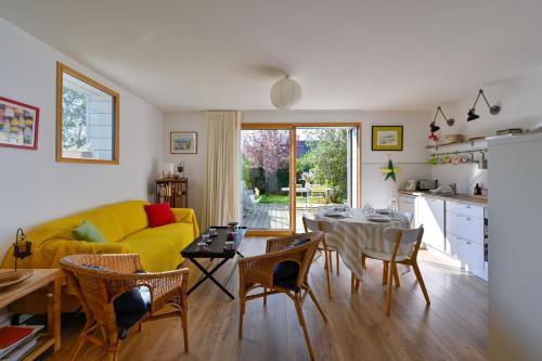 un salon avec un canapé jaune et une table dans l'établissement L'Annëxe de Kerogile - Avec jardin et terrasse, à Carnac