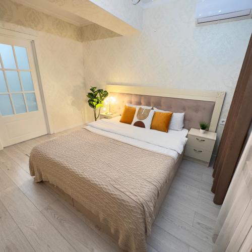 a bedroom with a large bed with orange pillows at Urban Oasis 216 in Almaty