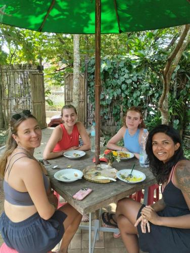 a group of women sitting at a table under an umbrella at Condro Wulan Hostel in Malang